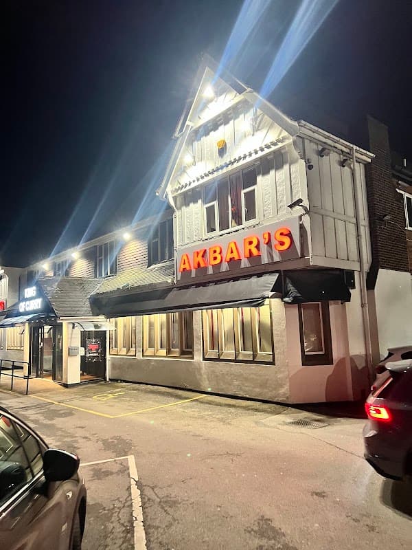 Brightly lit building with "AKBAR'S" sign, parked cars, and a dark night sky in Rotherham, Yorkshire.
