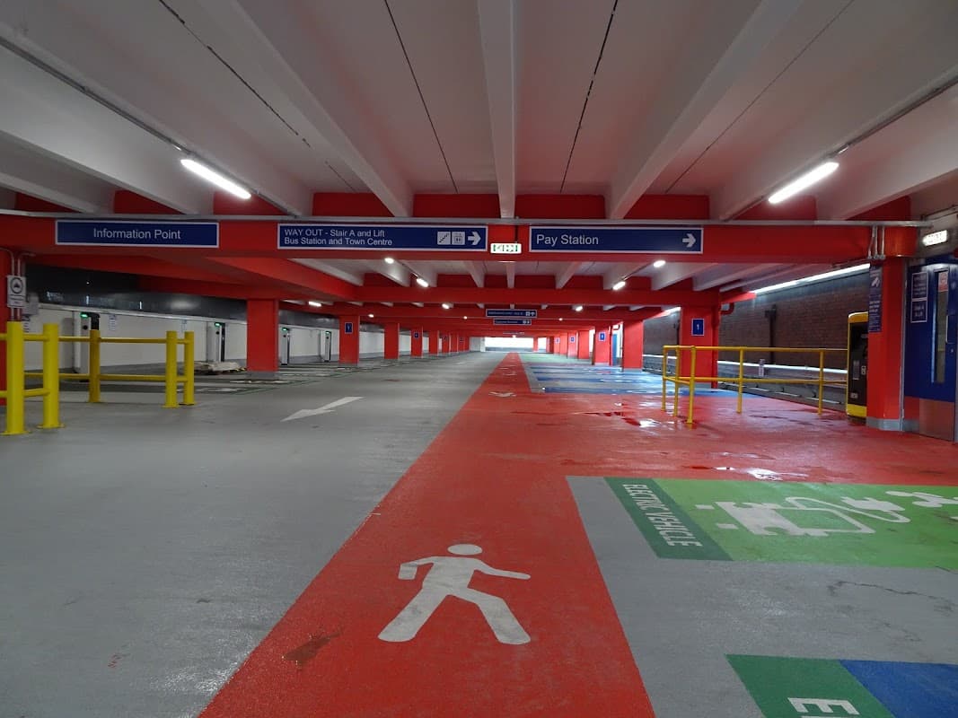 Multi-storey car park interior with clear signage, painted pedestrian paths, and an information point.