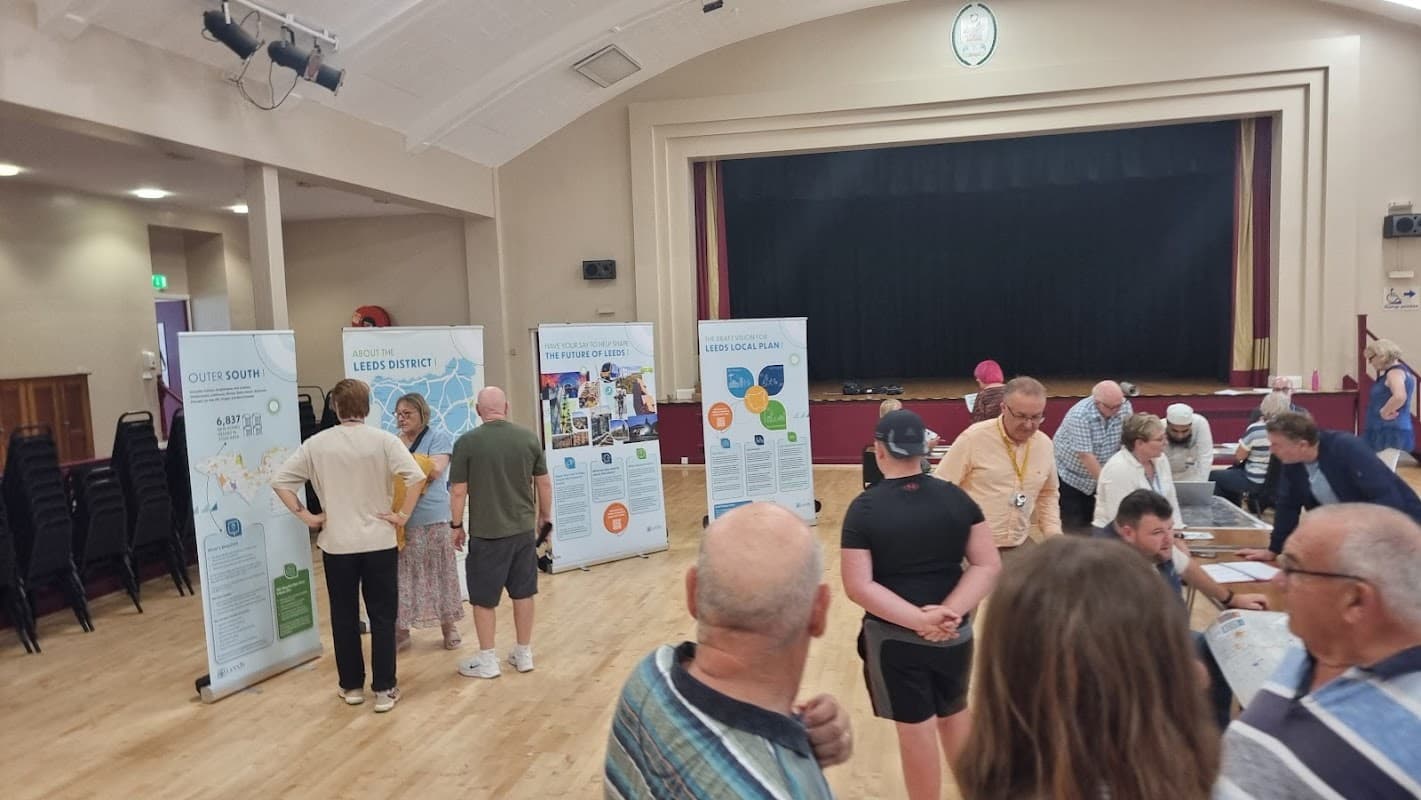 Car park with parked cars, surrounded by greenery and signage indicating Blackburn Hall in Rothwell, Yorkshire.