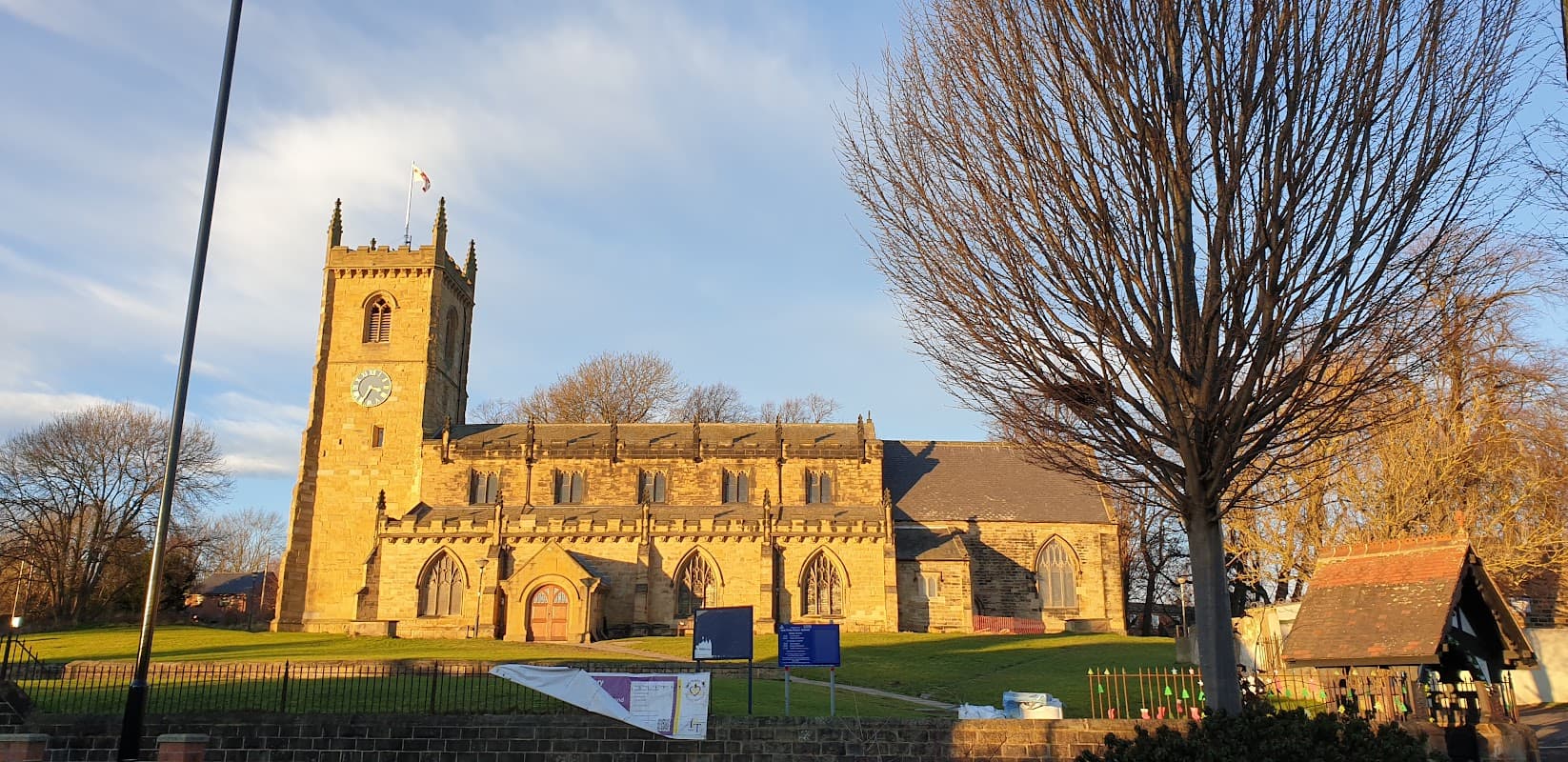 Church Street Car Park with a historic stone church, trees, and a clear blue sky in Rothwell, Yorkshire.