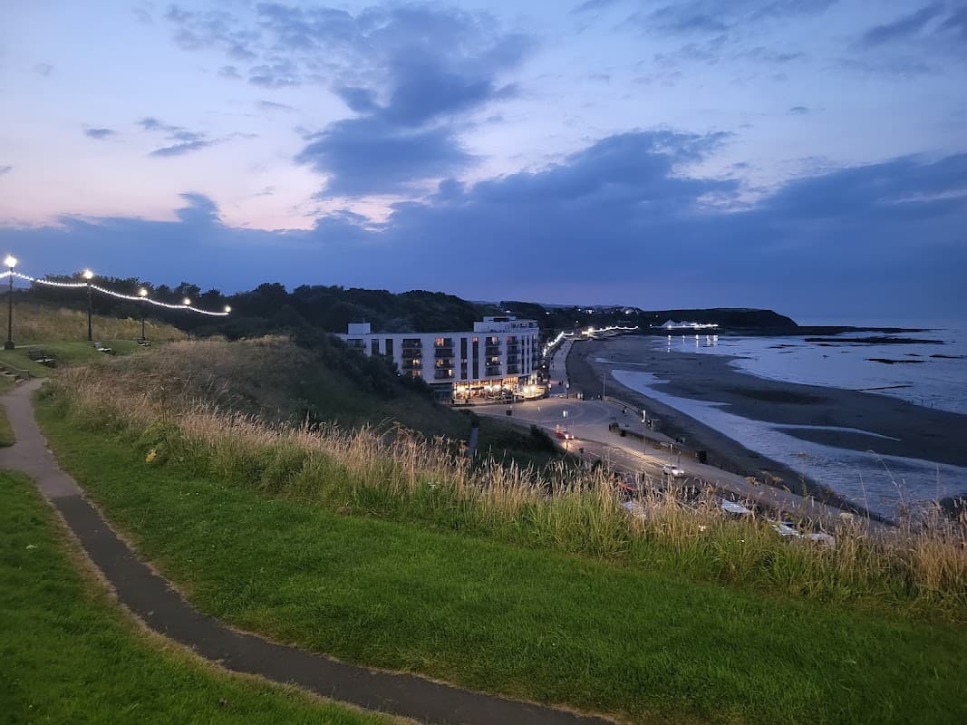 North Street Car Park overlooks a beach at dusk, with lights along the path and buildings in the background.