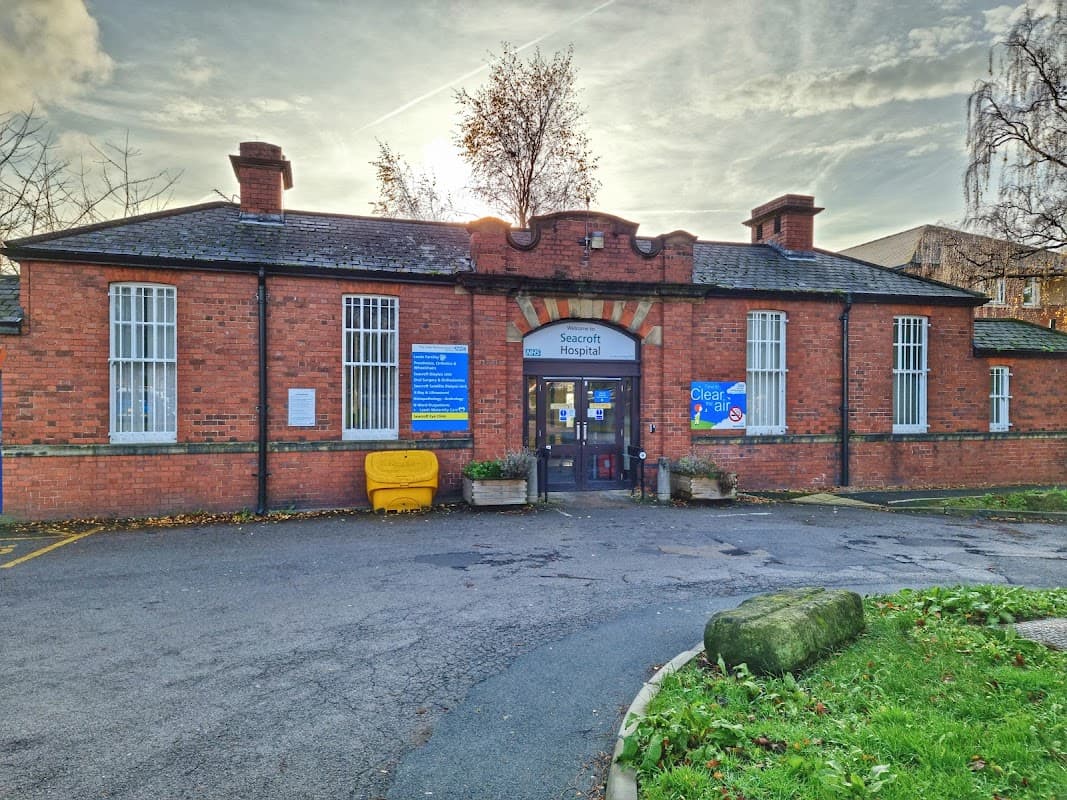 Seacroft Hospital's brick facade features a central entrance, signage, and surrounding greenery under a cloudy sky.