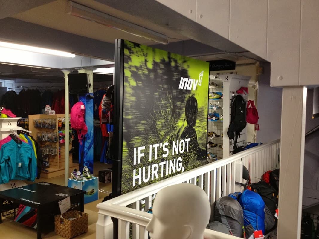 Indoor shop display at Castleberg Outdoors featuring colorful outdoor clothing and gear, with a prominent "IF IT'S NOT HURTING" sign.