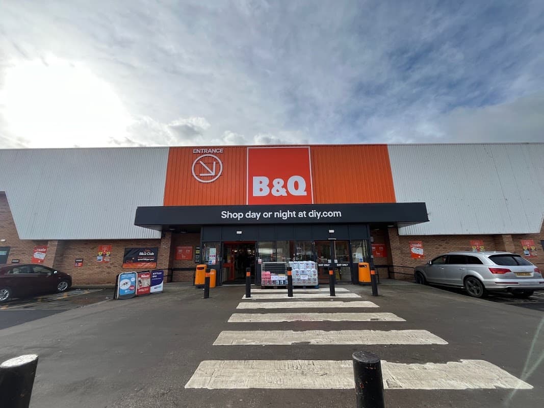 B&Q store entrance on Penistone Road, featuring a large orange and white sign, with parking and crosswalk in front.