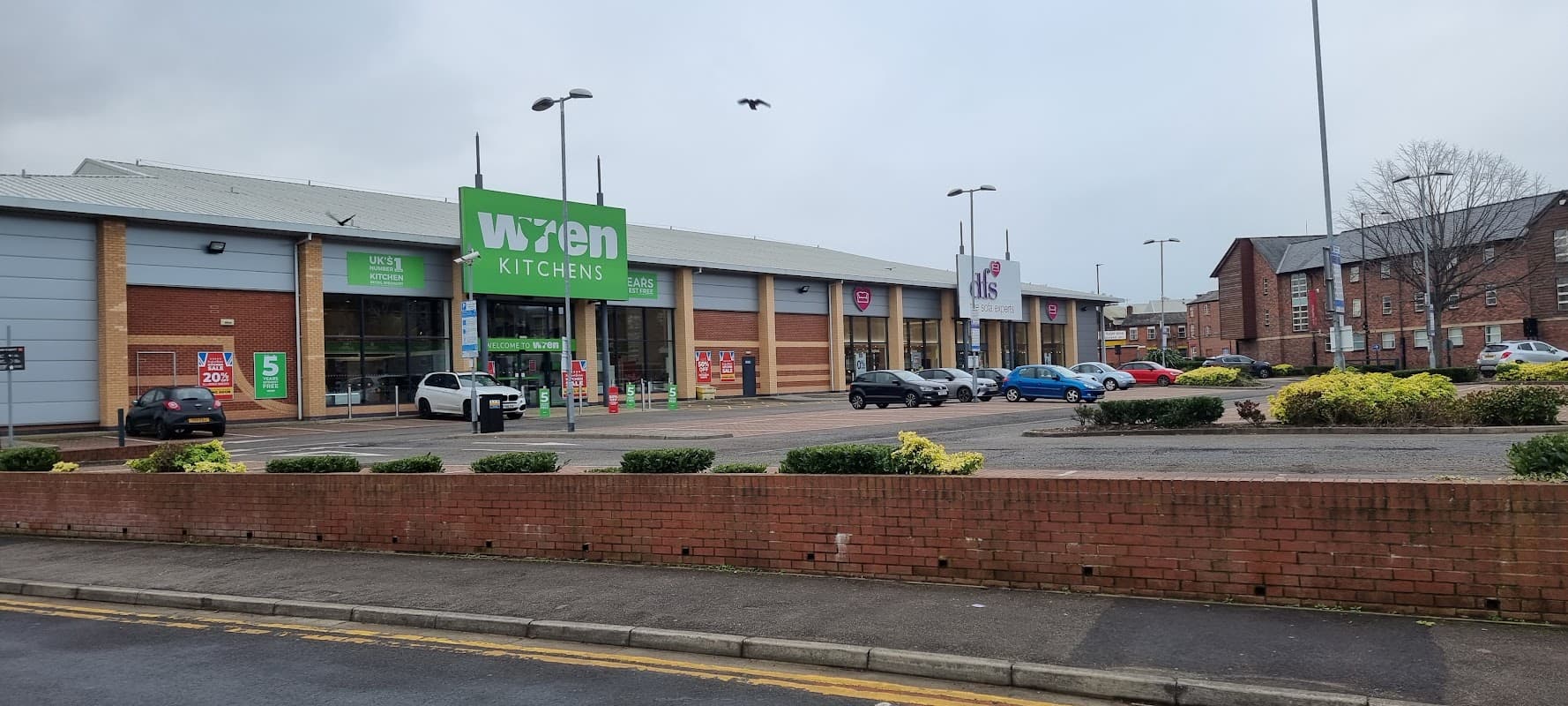 Exterior view of DFS Sheffield, featuring Wren Kitchens, with parked cars and landscaped areas.