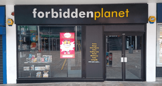 Bookshop storefront with "forbidden planet" sign, featuring colorful window displays and a large poster.