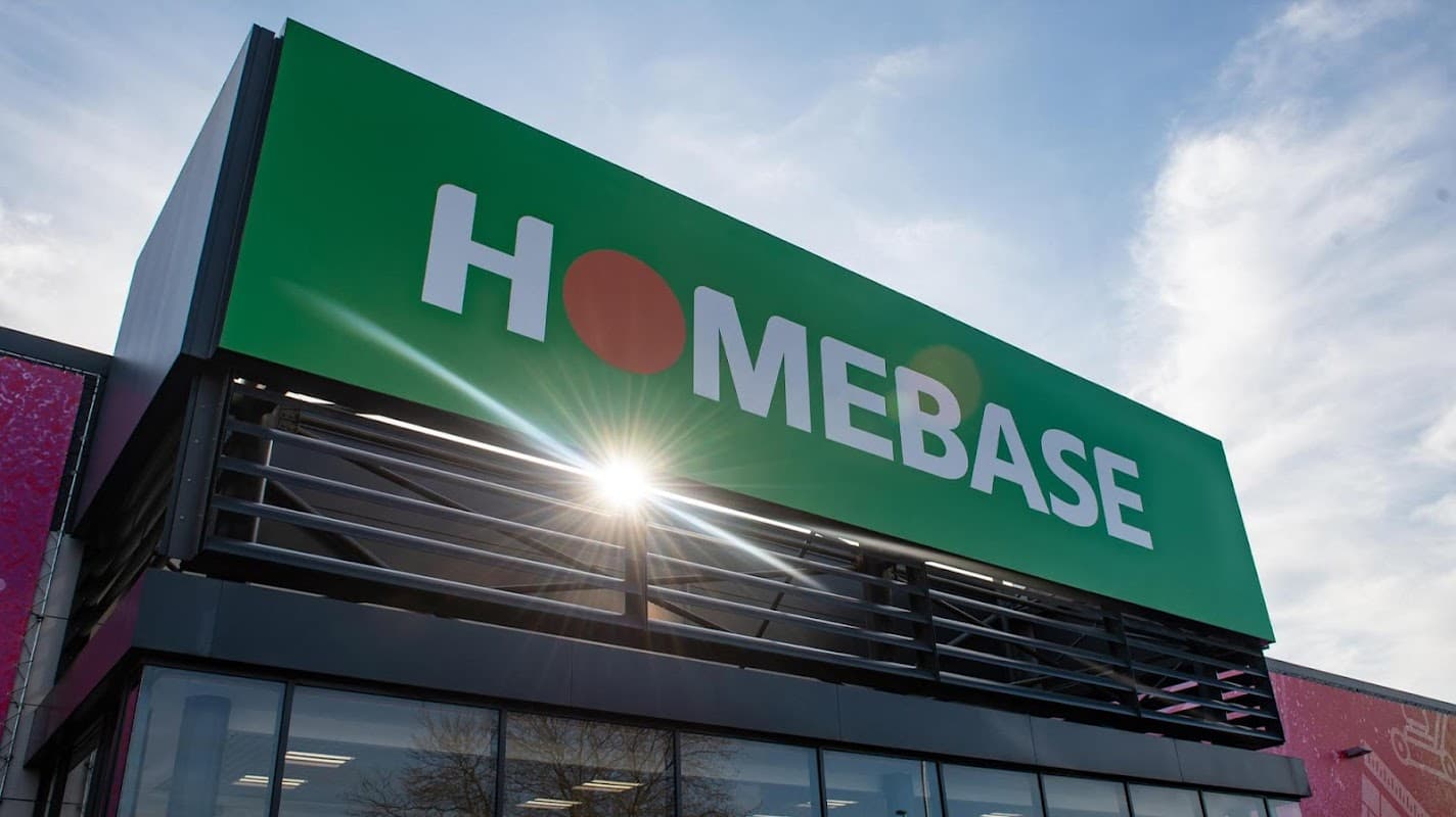 Bright green Homebase sign with a red dot, featuring a modern exterior and clear blue sky backdrop.