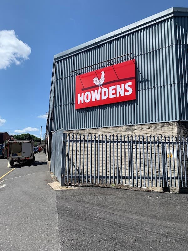 Howdens sign on a corrugated metal building, with a clear blue sky and a fenced area in Sheffield, Yorkshire.