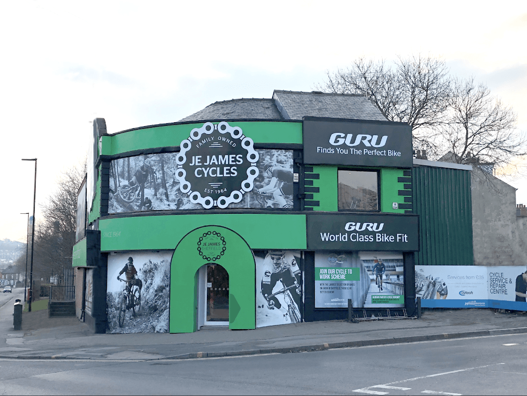 Green and black bike shop exterior with large signage for "J E James Cycles" and "GURU" in Sheffield, Yorkshire.