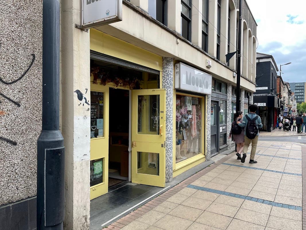 Bright yellow storefront of Moonko florist, with floral displays visible in the windows, situated on a busy street.