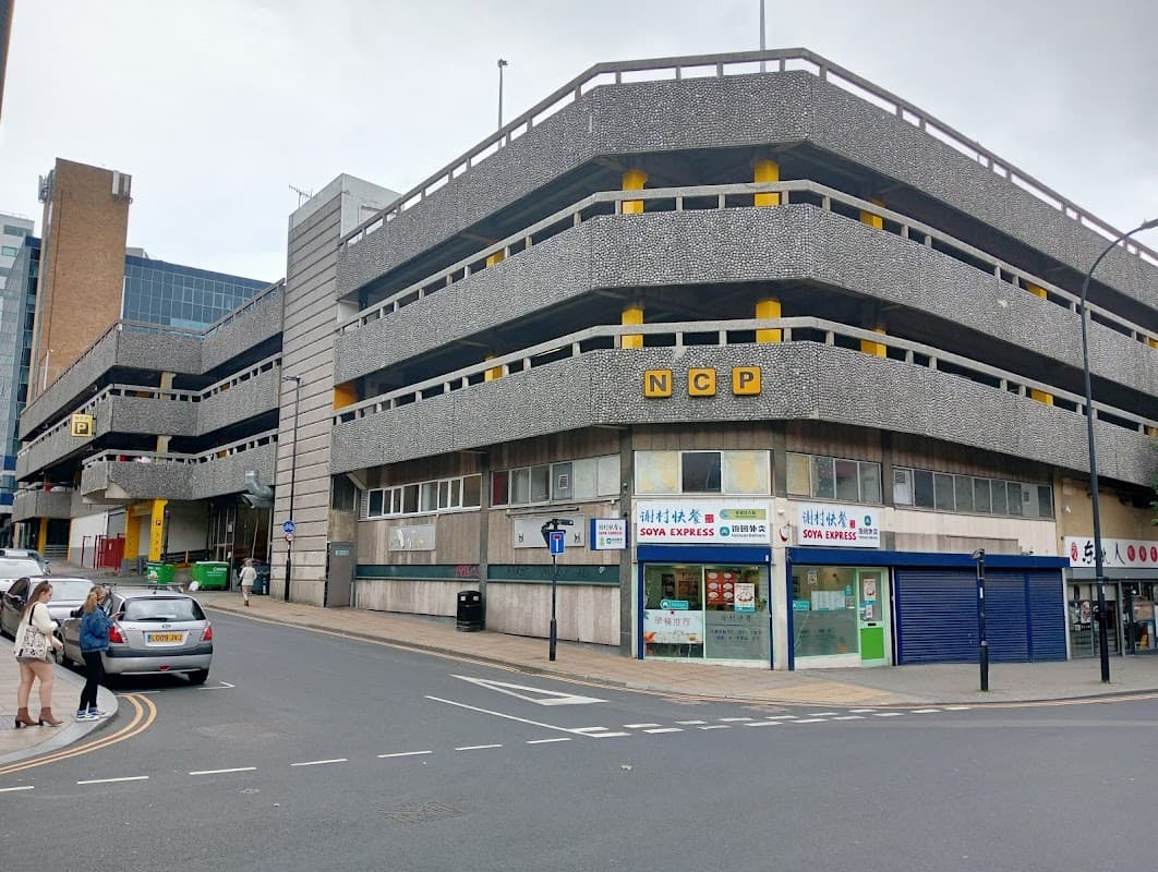 NCP parking garage with gray concrete structure, yellow accents, and nearby shops on Furnival Gate, Sheffield.