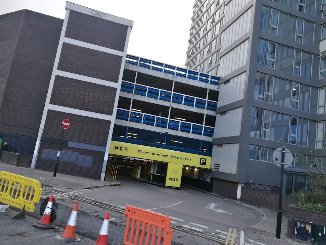 NCP Wellington Street car park entrance with barriers, signage, and adjacent modern buildings in Sheffield.