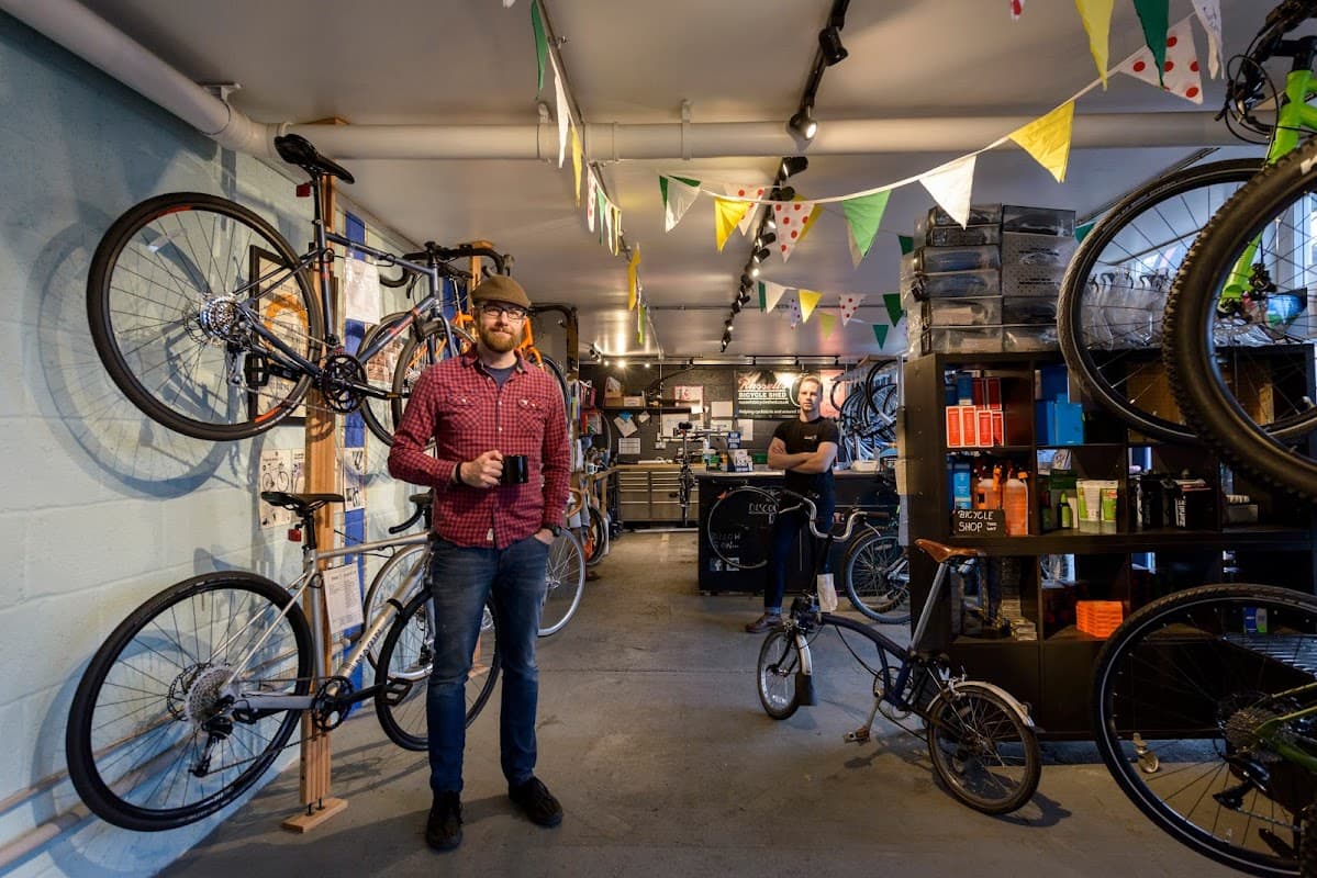 Interior of Russell's Bicycle Shed with bikes on display, a man holding a mug, and colorful bunting overhead.