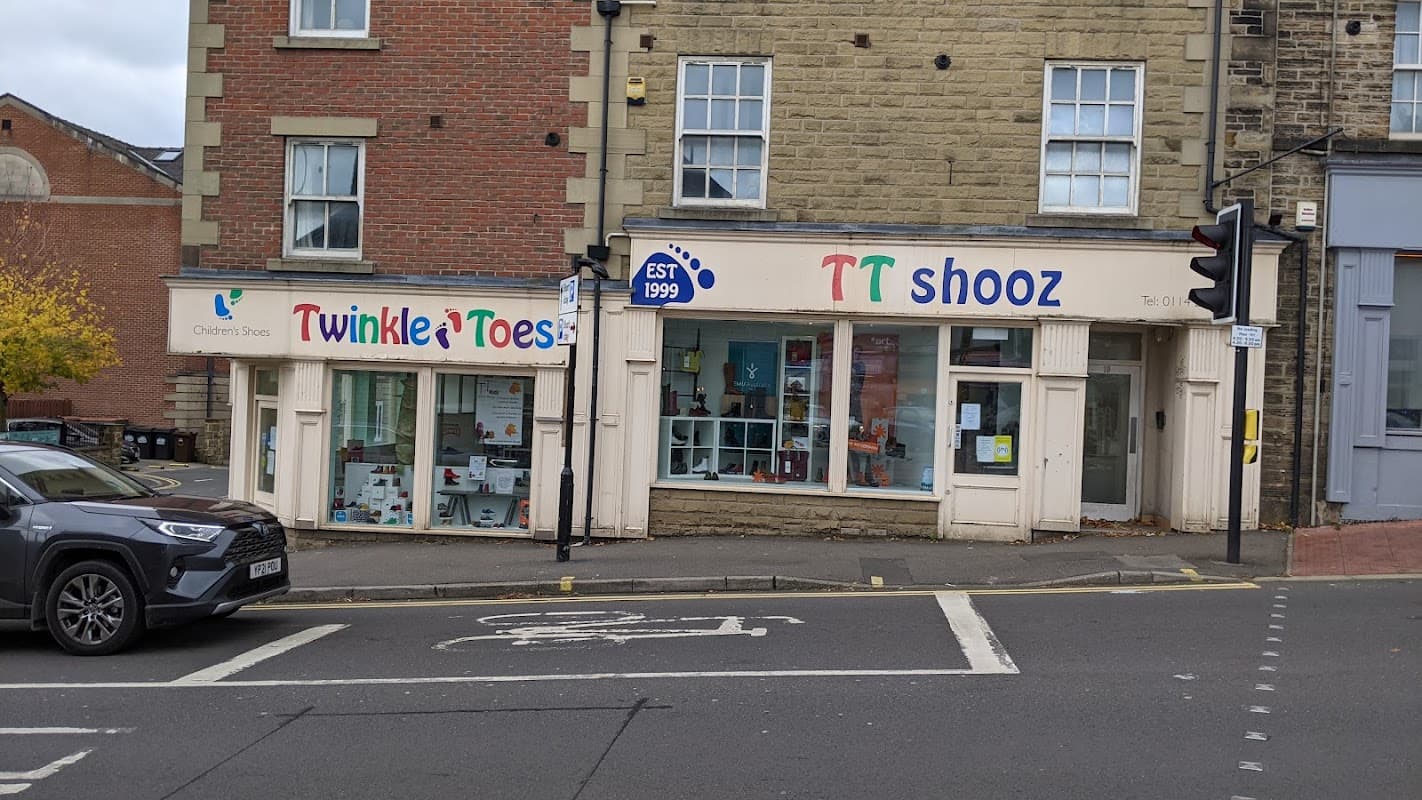 Colorful storefronts of "Twinkle Toes" and "TT Shooz," featuring children's shoes, in a Sheffield street setting.