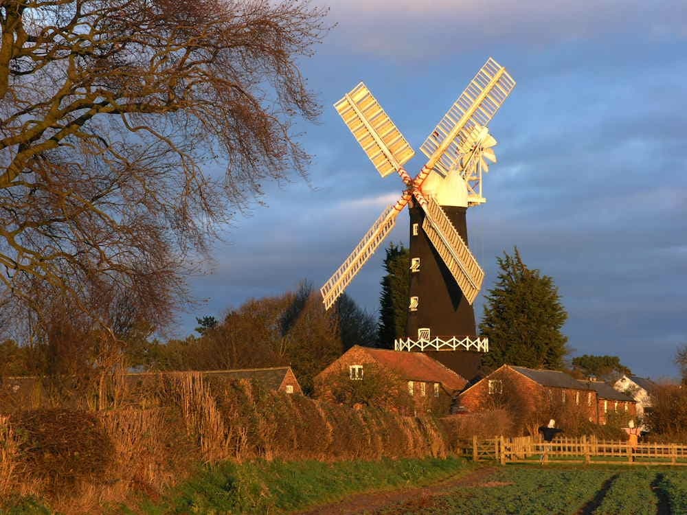 Skidby Mill stands tall with white sails, surrounded by lush greenery and a tranquil sky at sunset.