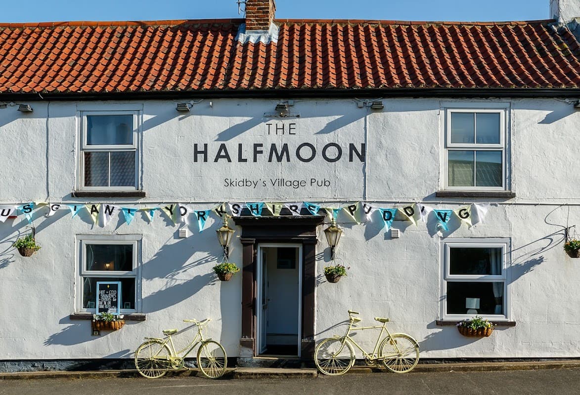 Charming white pub with a red-tiled roof, yellow bicycles, and decorative bunting in Skidby, Yorkshire.
