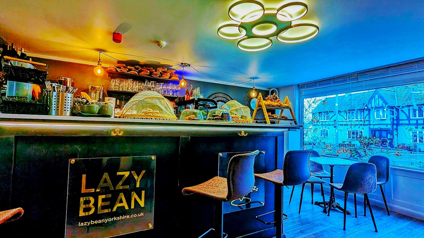 Cozy café interior with a sleek bar, illuminated display of pastries, and modern lighting, overlooking a quaint street.