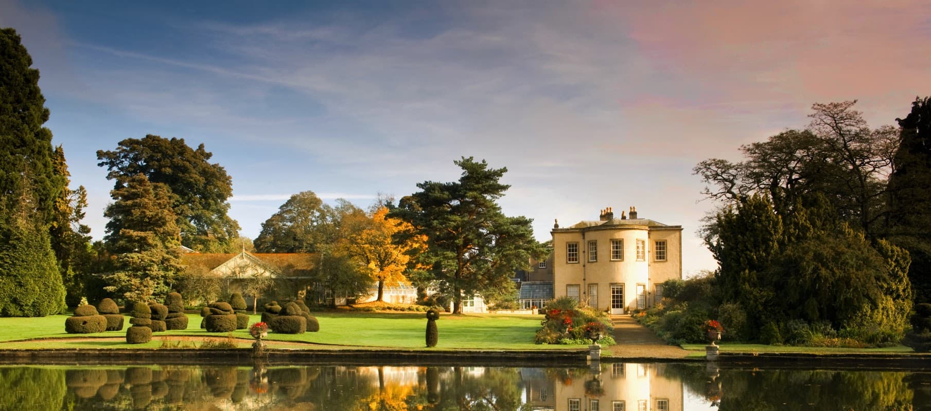 Thorp Perrow features manicured gardens, a tranquil lake, and a historic building surrounded by lush trees.