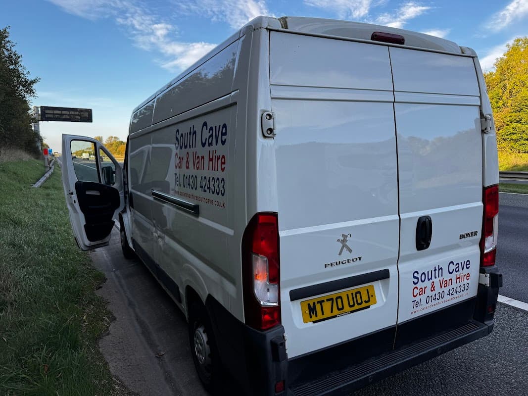 White van with "South Cave Car & Van Hire" branding parked by the road, with an open driver's door.