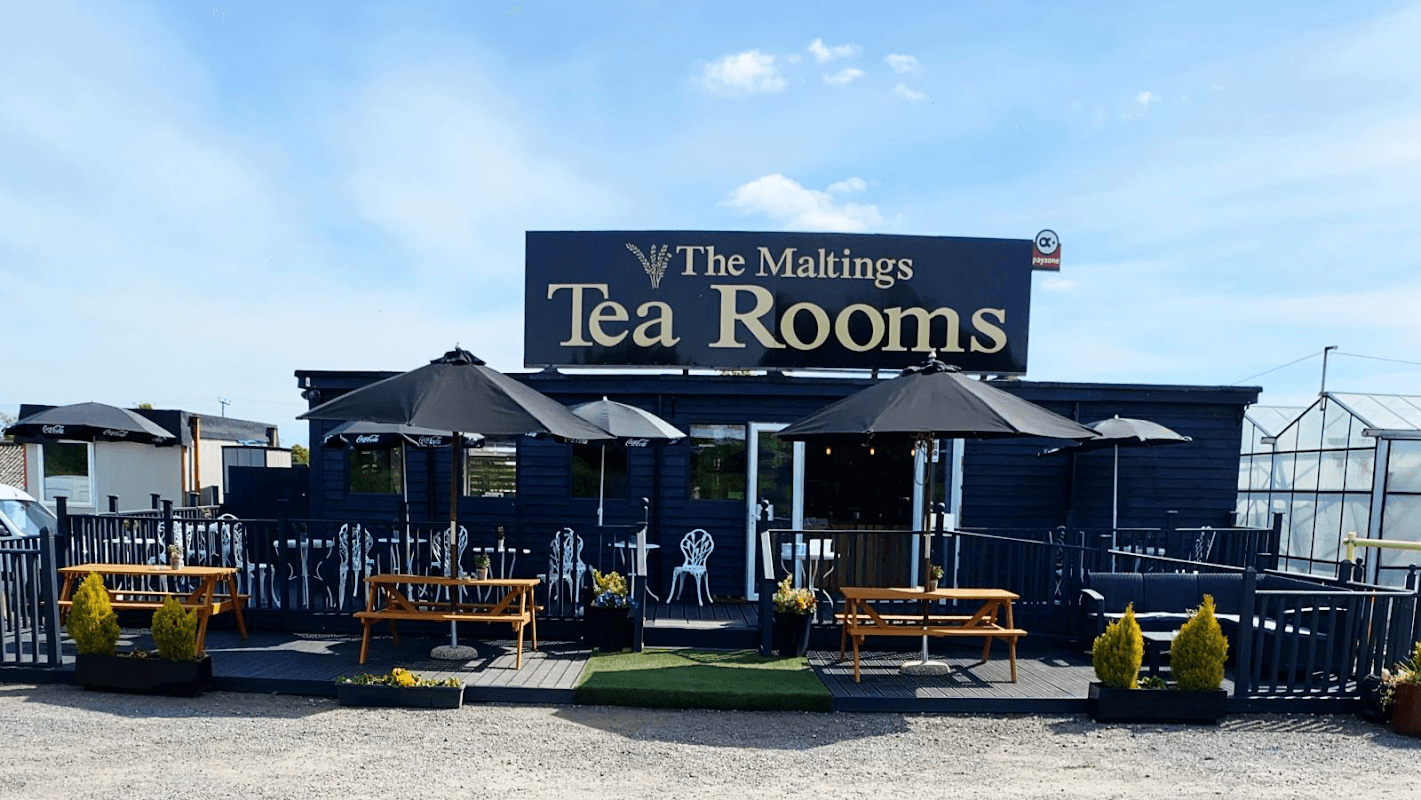 The Maltings Tea Rooms features outdoor seating, umbrellas, and a welcoming entrance in a rural setting.