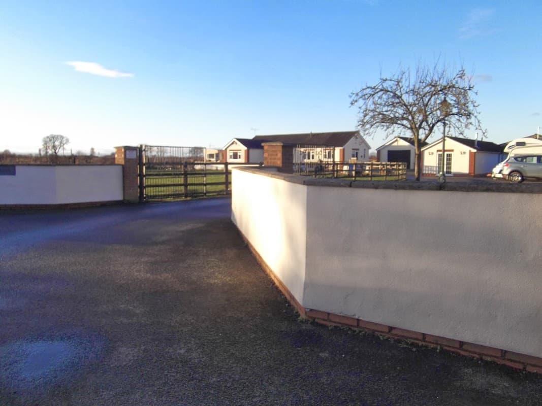Entrance gate to The Ranch Caravan Site, with a view of holiday homes and green fields in the background.