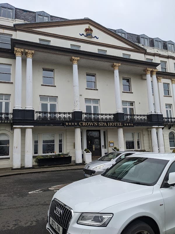 Elegant building with columns, "CROWN SPA HOTEL" sign, and parked white car in front, set in Spa Bridge, Yorkshire.