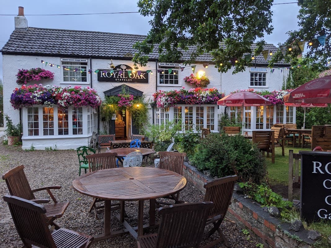Charming bar with floral displays, outdoor seating, and string lights, set in a cozy Yorkshire village.