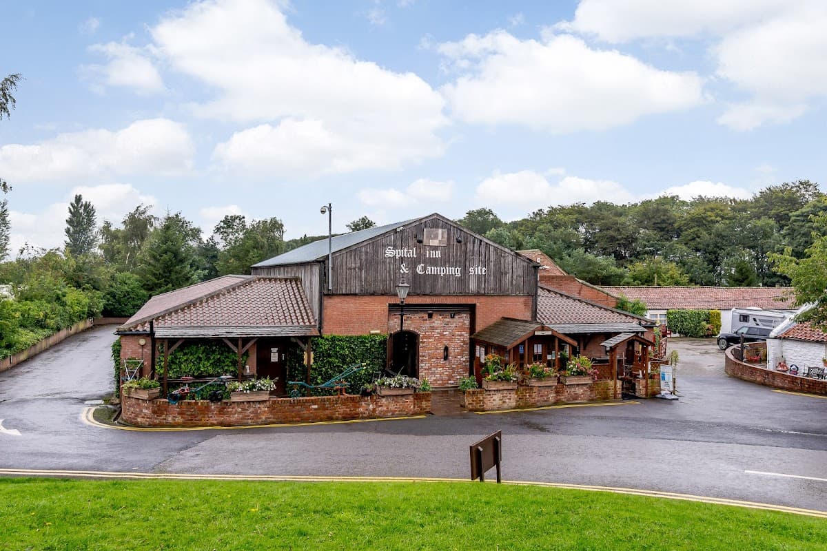 Spital Farm Camping Site & Themed Shopping Centre with rustic buildings, greenery, and a winding driveway in Yorkshire.