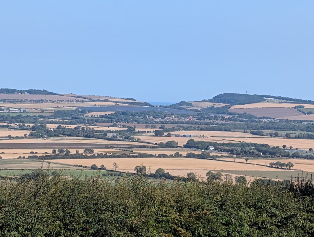 Rolling hills and patchwork fields under a clear blue sky, with distant coastal views in Staxton, Yorkshire.