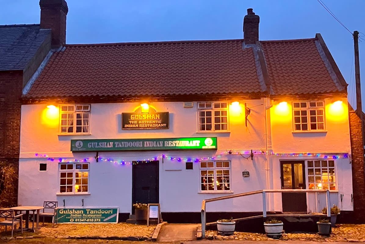 Gulshan Tandoori takeaway with warm lights, green signage, and festive decorations in Stillington, Yorkshire.