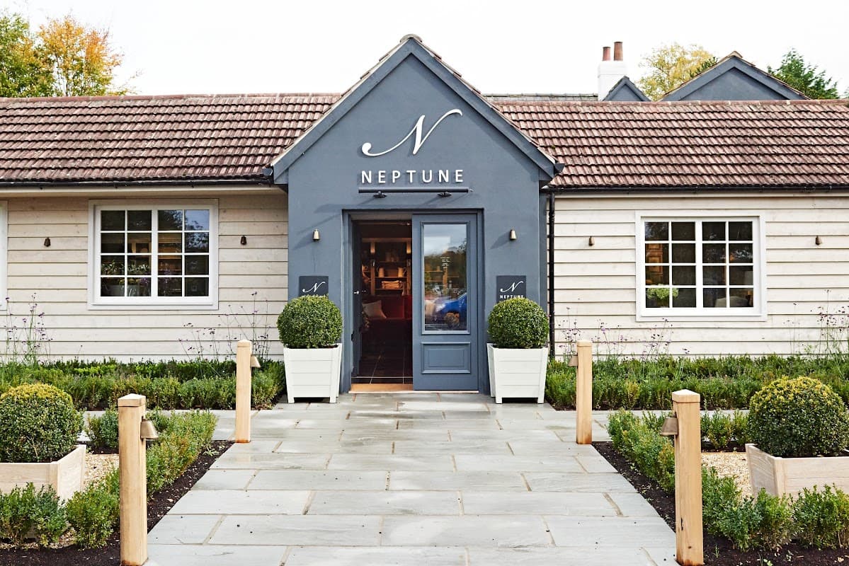 Charming homeware store with a grey facade, large windows, and neatly trimmed boxwood plants flanking the entrance.