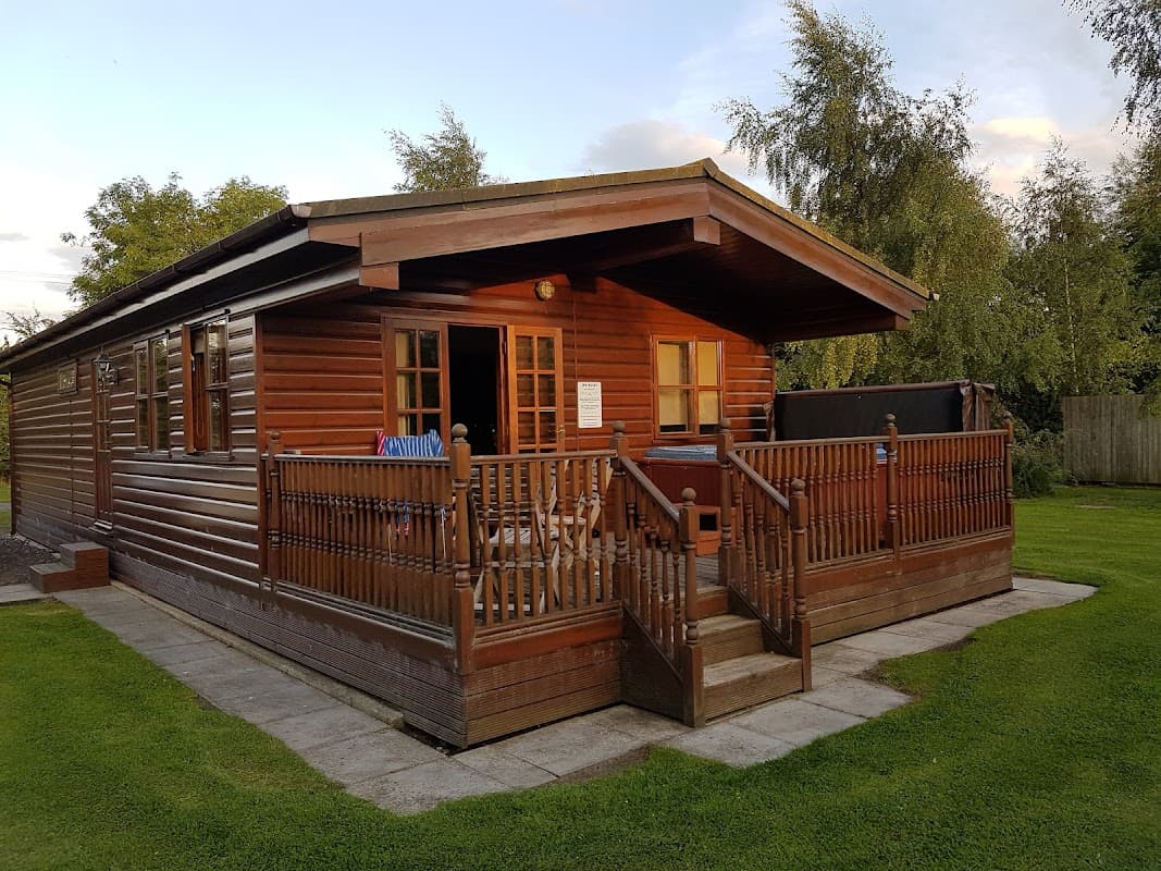 Wooden holiday lodge with a porch, surrounded by greenery and a clear sky in Sutton upon Derwent, Yorkshire.