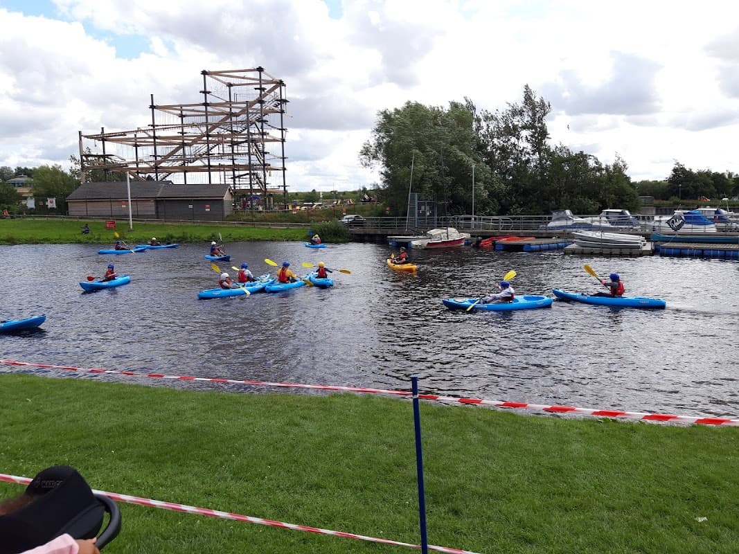 Kayakers on a river at Tees Barrage, with a construction site and trees in the background.