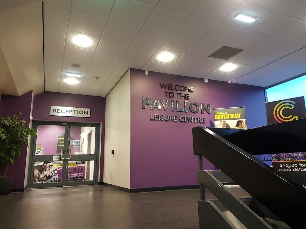 Reception area of Thornaby Pavilion with purple walls, signage, and a staircase leading to upper levels.
