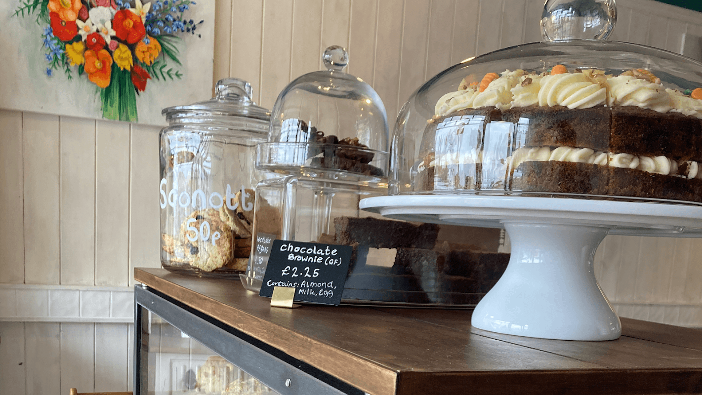Display of baked goods including a chocolate brownie, layered cake, and jars of cookies at Tea Time Café in Thirsk.