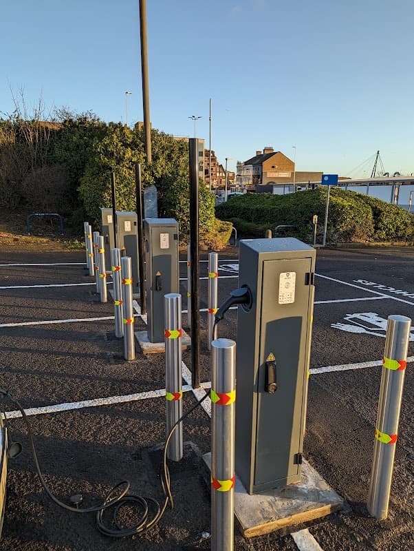 Pay & Display car park with charging stations, metal posts, and green shrubbery in Thornaby, Yorkshire.