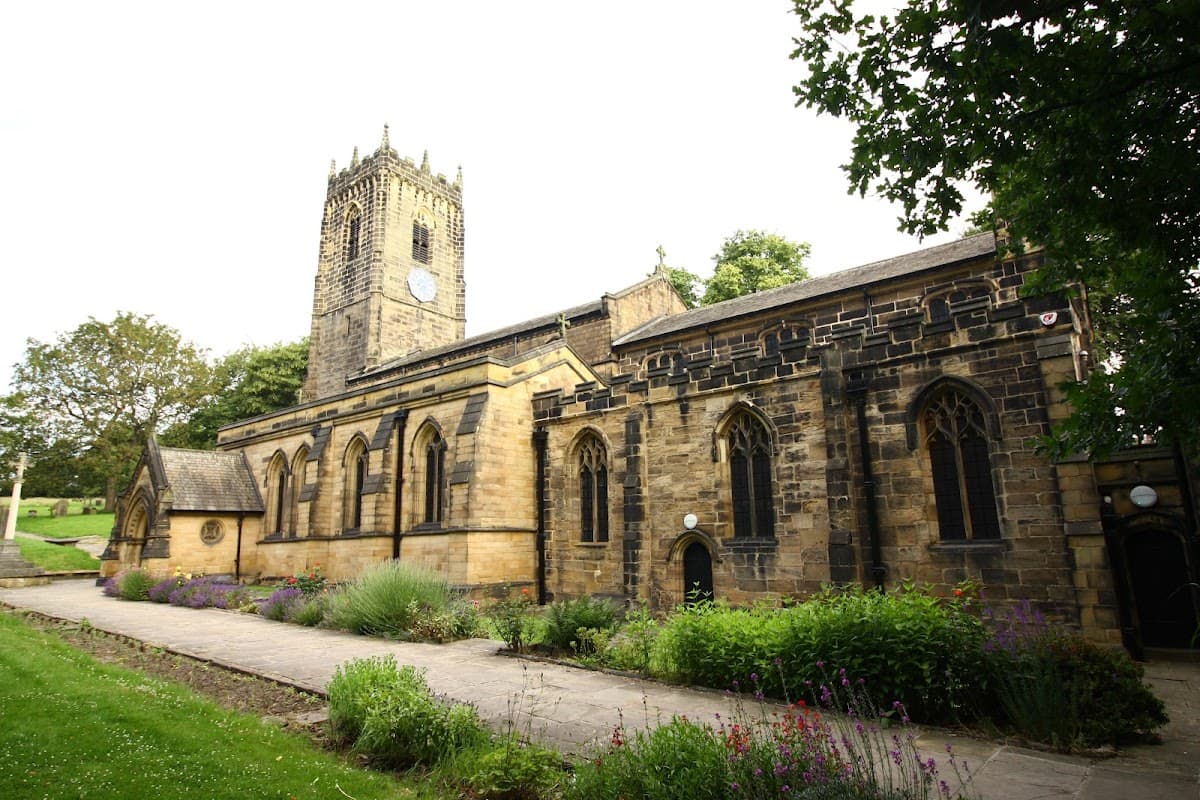 Thornhill Parish Church features a tall clock tower and stone facade, surrounded by green lawns and flowering plants.