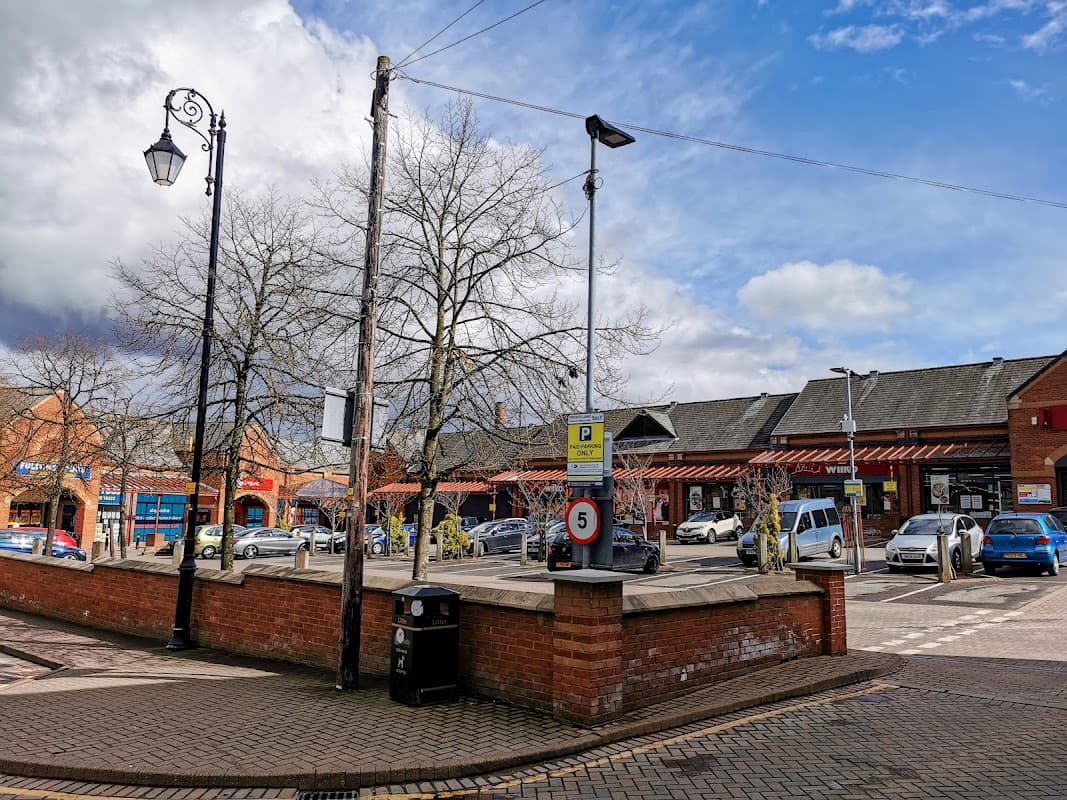 Market Square Car Park in Tingley, featuring pay & display signage, parked cars, and surrounding trees under a cloudy sky.