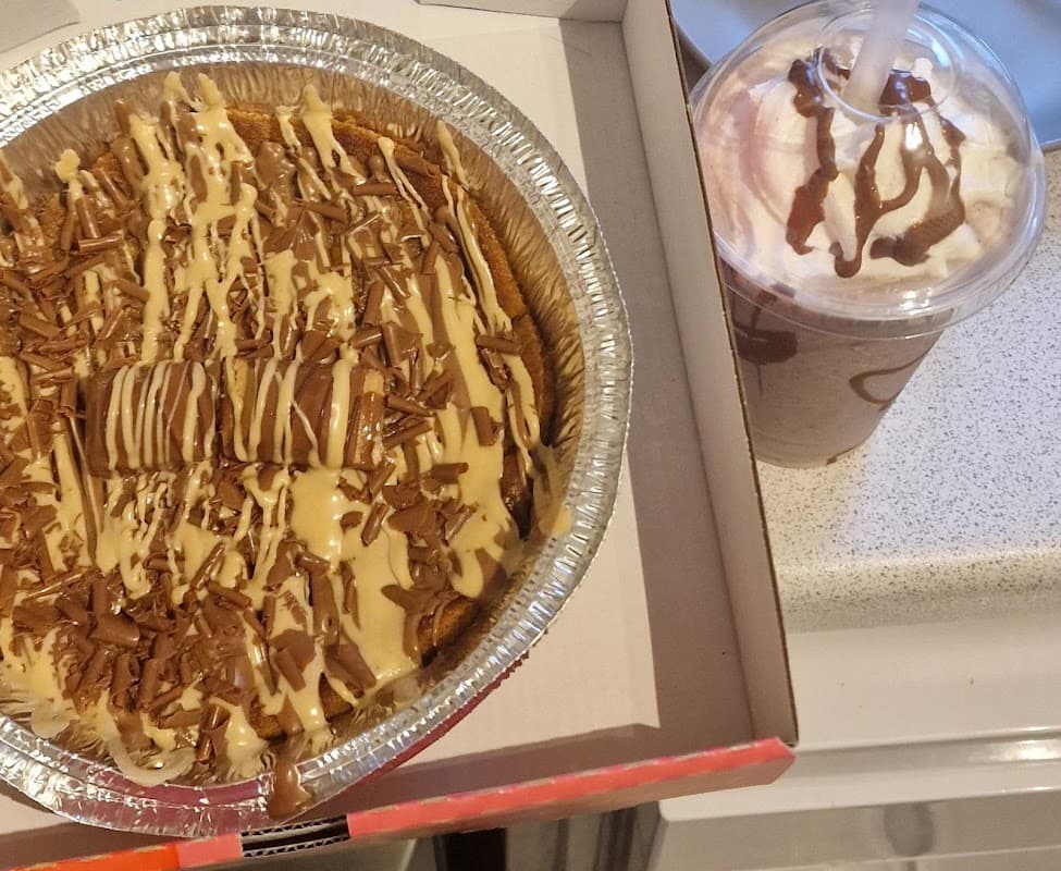 Decadent dessert with chocolate drizzle and sprinkles alongside a creamy drink topped with whipped cream and chocolate.