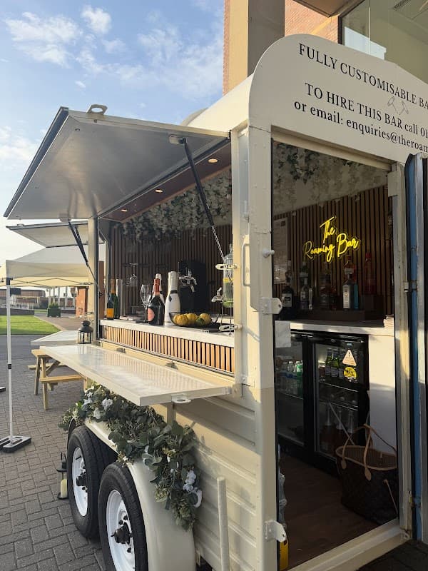 A mobile bar with a wooden counter, drinks displayed, and a neon sign reading "The Roaming Bar" in Tockwith, Yorkshire.