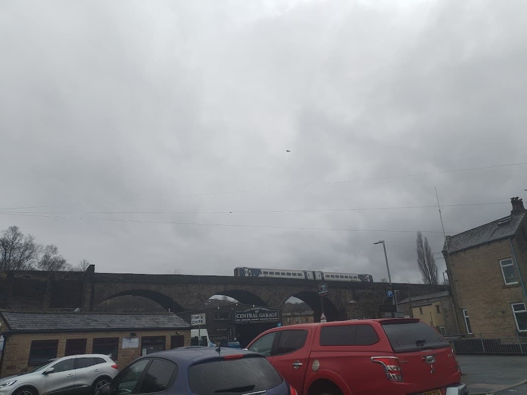 Dalton St Parking with cars, a railway viaduct above, and overcast skies in Todmorden, Yorkshire.