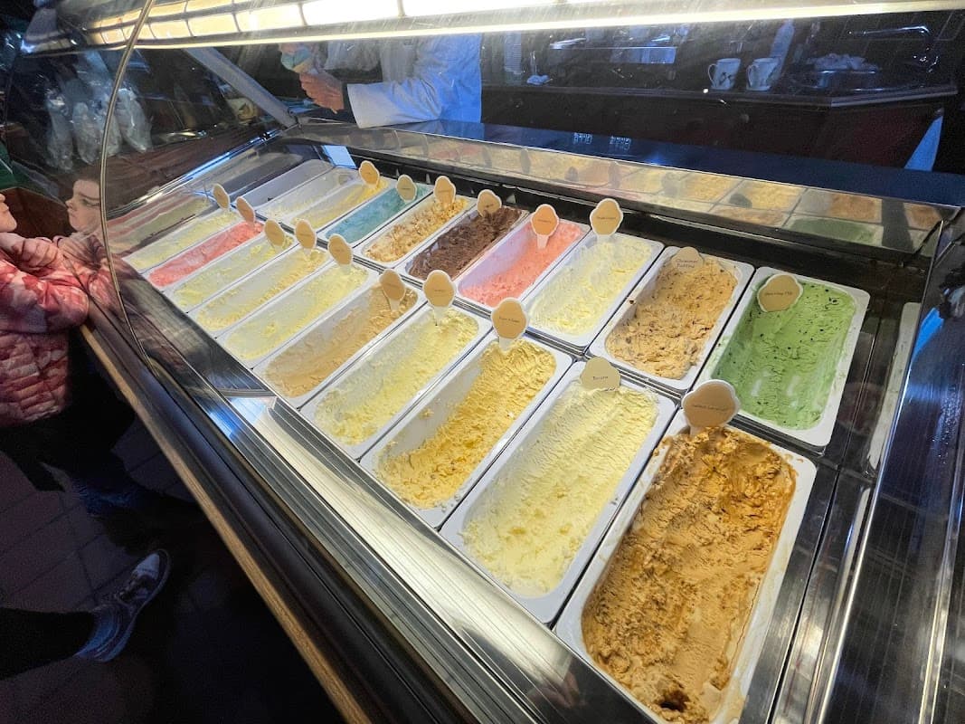 Colorful selection of gelato in a display case at Goodalls of Tong, with customers in the background.