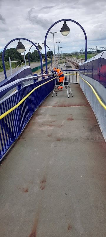A worker in high-visibility gear repairs a bridge at Ulleskelf bus stop, with tracks visible in the background.