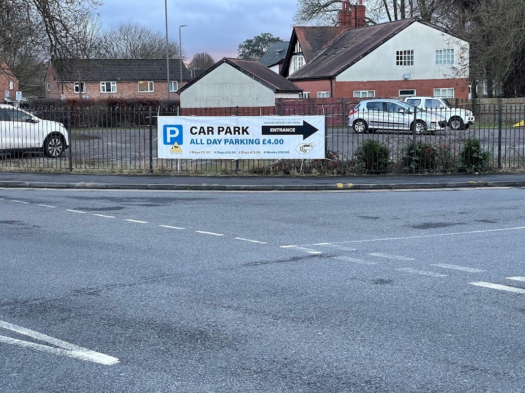 Bevan Grove Car Park sign displaying £4 all-day parking, with nearby residential buildings and parked cars.