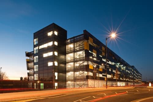 Modern multi-story car park with illuminated windows, streetlights, and a twilight sky in Wakefield, Yorkshire.