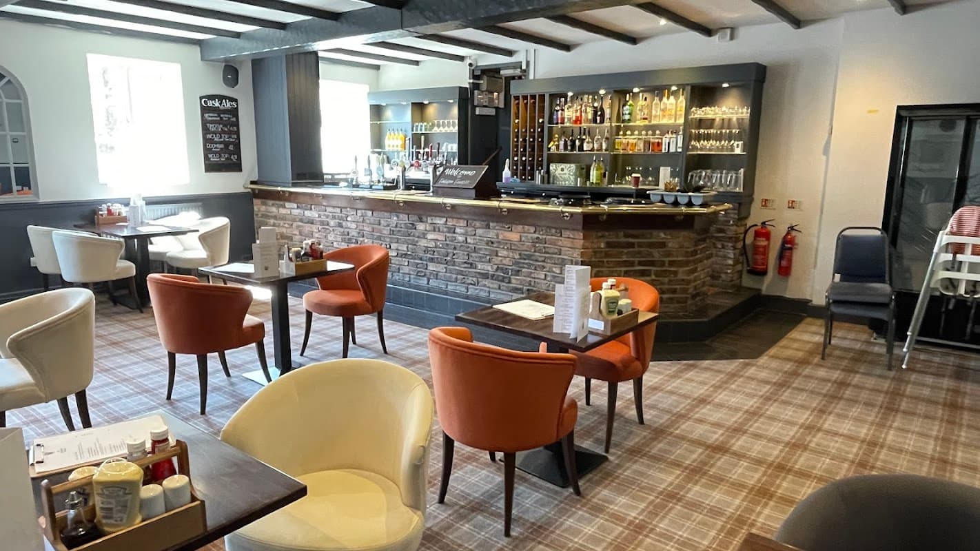 Cozy pub interior with wooden beams, a stone bar, colorful chairs, and a well-stocked bar shelf in Walkington, Yorkshire.