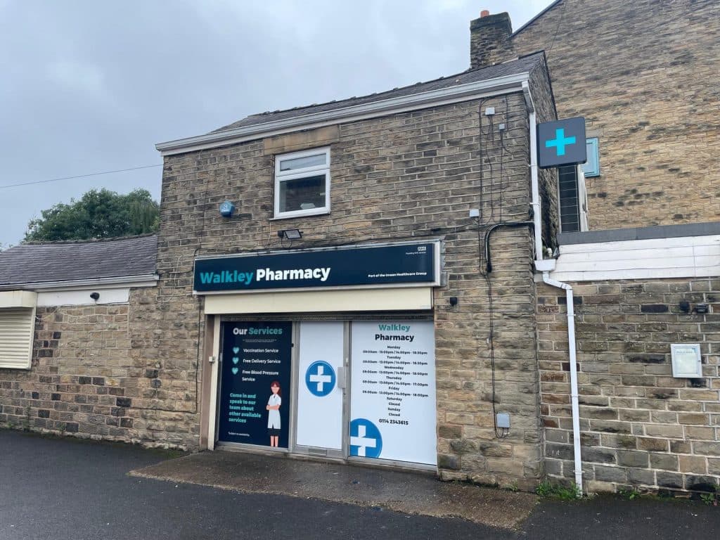 Walkley Pharmacy building with stone facade, signage for vaccination and travel clinic, and a blue cross symbol.