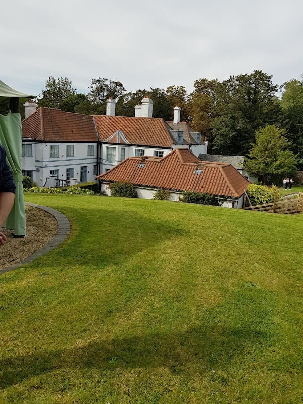 Welton Lodge features a charming hotel building with red-tiled roofs, surrounded by lush green lawns and trees.