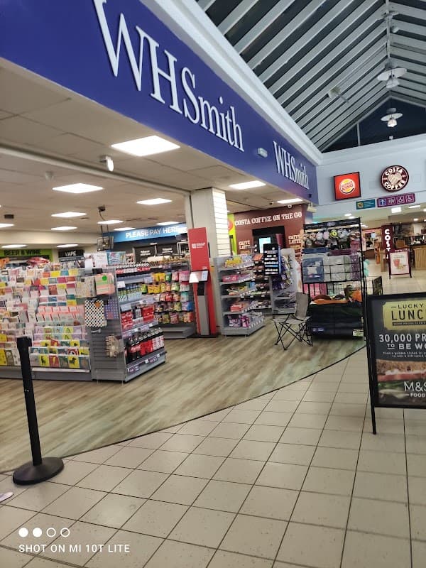 WHSmith store interior featuring books, cards, and a Costa Coffee counter in a motorway service area.