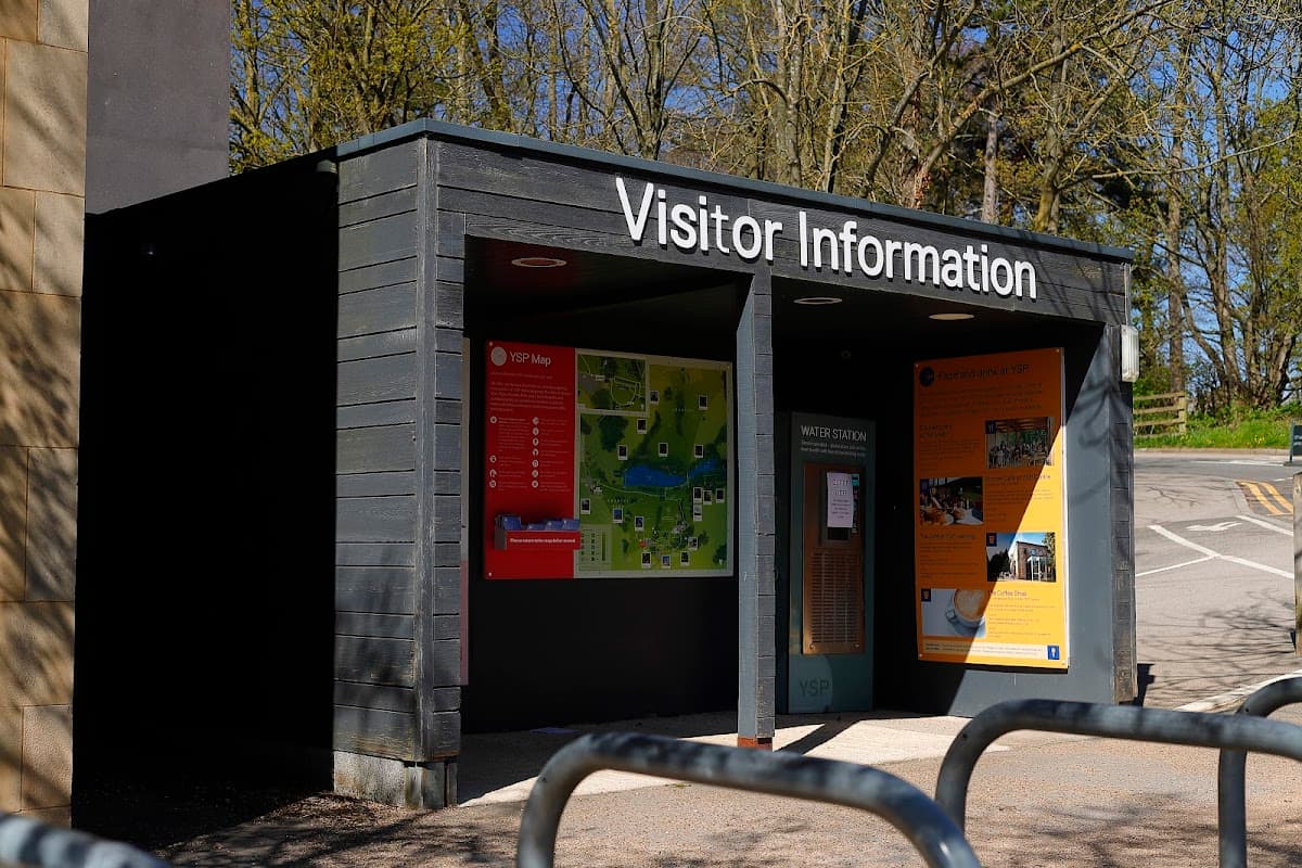 Visitor information center with a map, signage, and bike racks outside in a wooded area.
